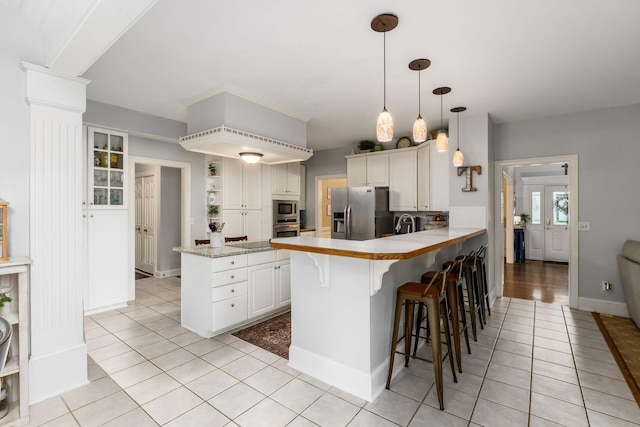 1828 Bradford Cir, Newark, OH 43055 - kitchen with appliances with stainless steel finishes, a peninsula, light tile patterned floors, a kitchen breakfast bar, and white cabinetry