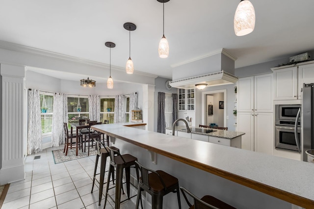 1828 Bradford Cir, Newark, OH 43055 - kitchen featuring appliances with stainless steel finishes, light tile patterned flooring, a kitchen bar, white cabinetry, and ornamental molding