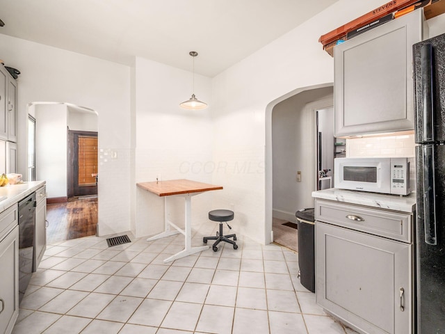 1482 Briarwood Ave, Columbus, OH 43211 - kitchen with arched walkways, white microwave, light countertops, stainless steel dishwasher, and light tile patterned floors