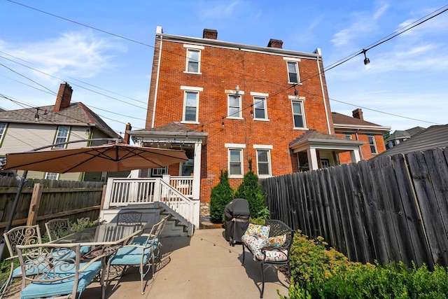 144 Wilson Ave, Columbus, OH 43205 - rear view of house with brick siding, a fenced backyard, a patio, and a chimney