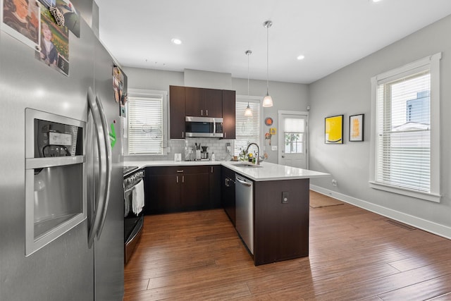 144 Wilson Ave, Columbus, OH 43205 - kitchen featuring appliances with stainless steel finishes, a peninsula, dark brown cabinetry, light countertops, and recessed lighting