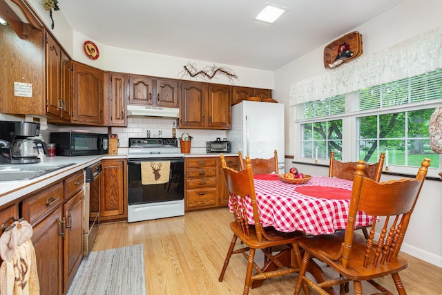 1374 Hanover Ct, Circleville, OH 43113 - kitchen with black appliances, under cabinet range hood, light countertops, light wood finished floors, and backsplash