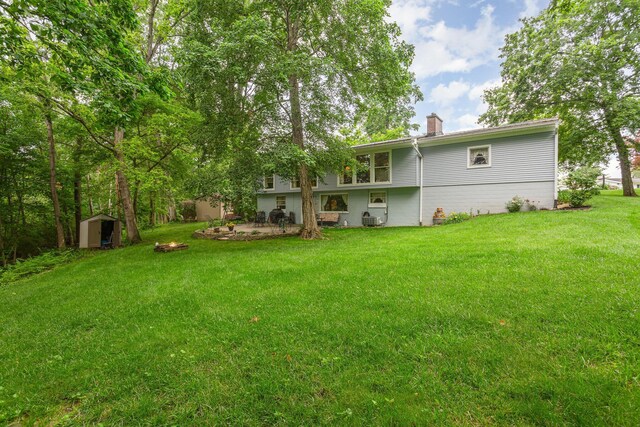 1374 Hanover Ct, Circleville, OH 43113 - back of house featuring a storage unit, a chimney, a lawn, and a fire pit