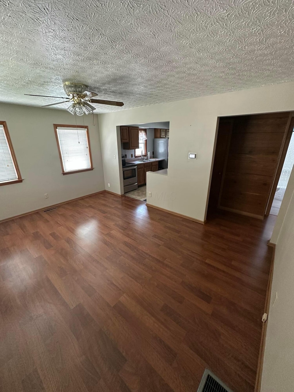 3203 Grasmere Ave, Columbus, OH 43224 - unfurnished living room featuring dark wood-style flooring, a ceiling fan, and a textured ceiling