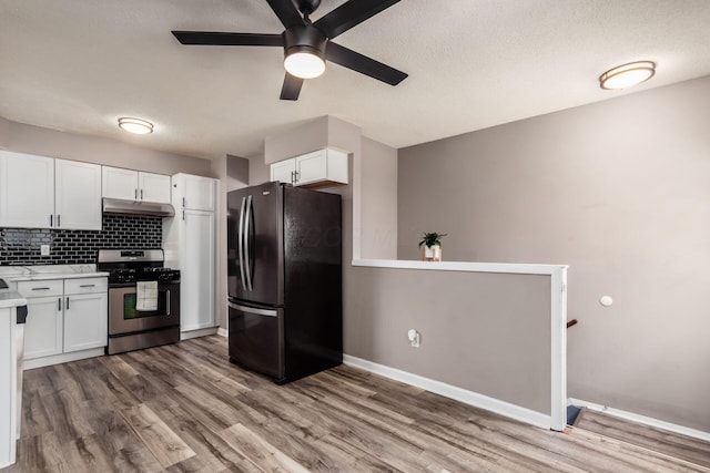 284 Blendon Rd, West Jefferson, OH 43162 - kitchen featuring freestanding refrigerator, stainless steel gas stove, under cabinet range hood, light countertops, and white cabinetry