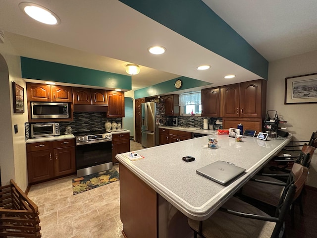 1080 Sycamore Dr, Lancaster, OH 43130 - kitchen featuring appliances with stainless steel finishes, a peninsula, light countertops, a kitchen breakfast bar, and recessed lighting
