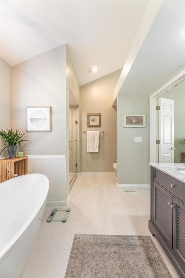 419 Wooten Ct S, Powell, OH 43065 - bathroom with vanity, a soaking tub, a stall shower, and lofted ceiling