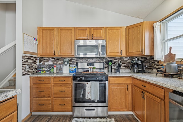 2587 Weeping Willow Ct, Columbus, OH 43207 - kitchen featuring appliances with stainless steel finishes, vaulted ceiling, tasteful backsplash, dark wood-style floors, and light stone countertops