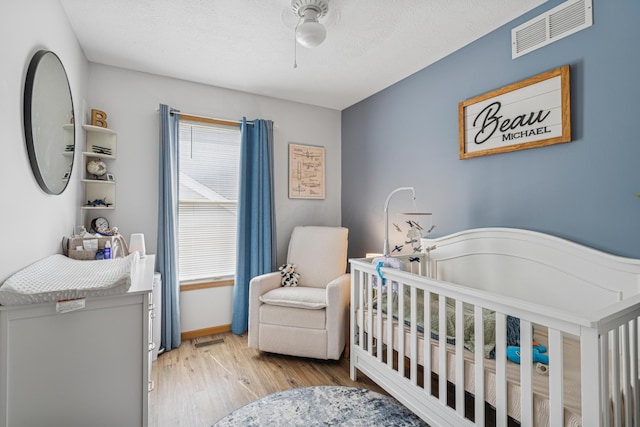 2587 Weeping Willow Ct, Columbus, OH 43207 - bedroom with wood finished floors, a crib, and ceiling fan