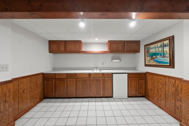 3625 Peany Ln, Canal Winchester, OH 43110 - kitchen featuring brown cabinets, wainscoting, light countertops, wood walls, and light tile patterned flooring