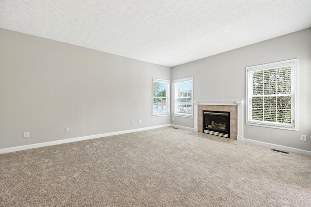 5497 Mirage Dr, Hilliard, OH 43026 - unfurnished living room with a tiled fireplace, plenty of natural light, carpet floors, and a textured ceiling