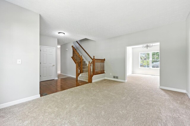 5497 Mirage Dr, Hilliard, OH 43026 - unfurnished living room with carpet flooring, stairway, a chandelier, and a textured ceiling