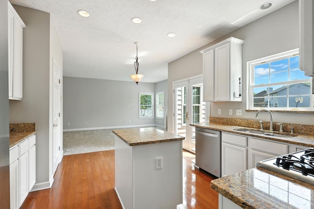 5497 Mirage Dr, Hilliard, OH 43026 - kitchen featuring stainless steel dishwasher, a center island, white cabinets, a textured ceiling, and hardwood / wood-style floors