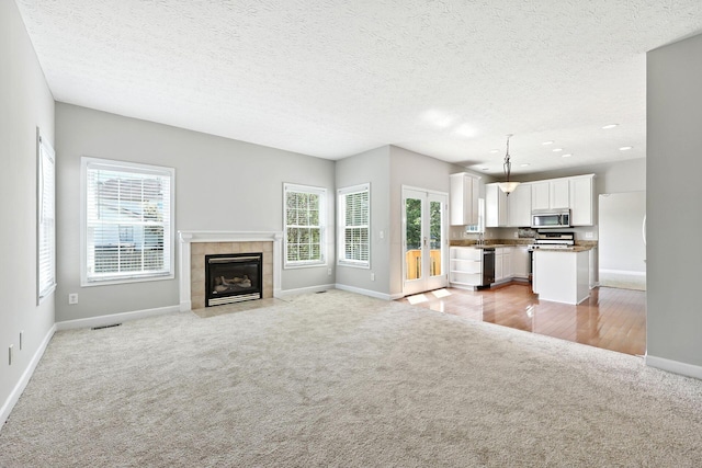 5497 Mirage Dr, Hilliard, OH 43026 - unfurnished living room featuring light carpet, plenty of natural light, a tile fireplace, recessed lighting, and a textured ceiling