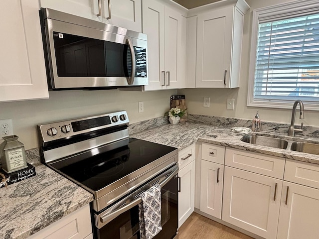 32 Maple St, Jeffersonville, OH 43128 - kitchen featuring appliances with stainless steel finishes, white cabinets, light wood-type flooring, and light stone counters