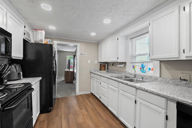 3053 E Old Duvall Ct, Lockbourne, OH 43137 - kitchen featuring black appliances, wood finished floors, white cabinetry, healthy amount of natural light, and a textured ceiling