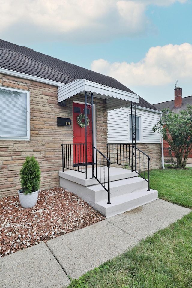 815 Eddystone Ave, Columbus, OH 43224 - view of exterior entry with stone siding, roof with shingles, and a lawn