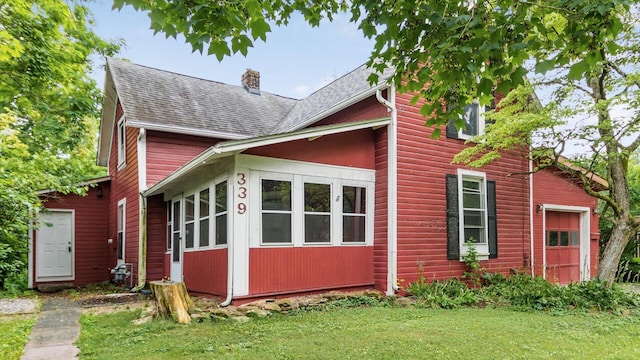 339 W Maple St, Granville, OH 43023 - view of home's exterior featuring a chimney, a shingled roof, a yard, a sunroom, and an attached garage