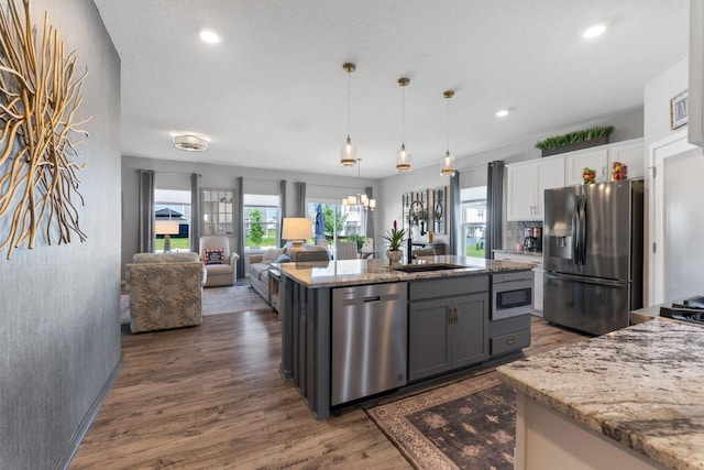 152 Natalie Ln, Granville, OH 43023 - kitchen with stainless steel appliances, white cabinetry, dark wood-style flooring, light stone countertops, and decorative light fixtures