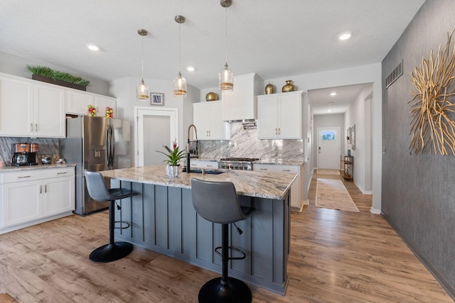 152 Natalie Ln, Granville, OH 43023 - kitchen with stainless steel refrigerator with ice dispenser, backsplash, light wood-style floors, a kitchen bar, and recessed lighting