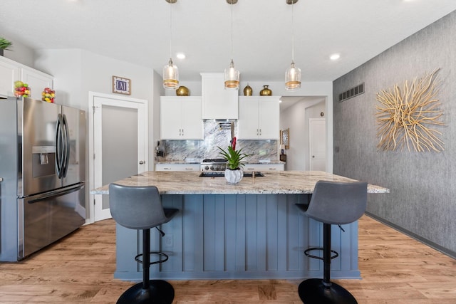 152 Natalie Ln, Granville, OH 43023 - kitchen with stainless steel fridge, white cabinets, light wood-style flooring, a kitchen bar, and recessed lighting