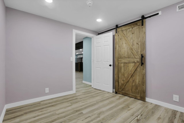 39703 Maysville Greendale Rd, Logan, OH 43138 - unfurnished bedroom featuring a barn door, light wood-type flooring, and recessed lighting