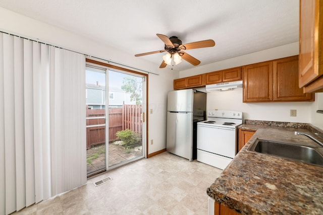 884 Annagladys Dr Unit F2, Columbus, OH 43085 - kitchen featuring freestanding refrigerator, white electric range oven, under cabinet range hood, brown cabinetry, and dark countertops