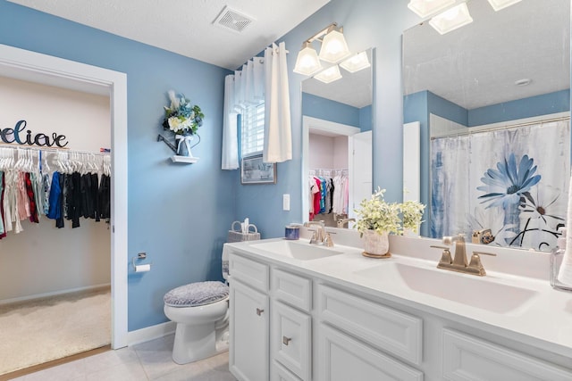 211 Talla Rd S, Delaware, OH 43015 - bathroom with double vanity, a walk in closet, tile patterned floors, a textured ceiling, and curtained shower