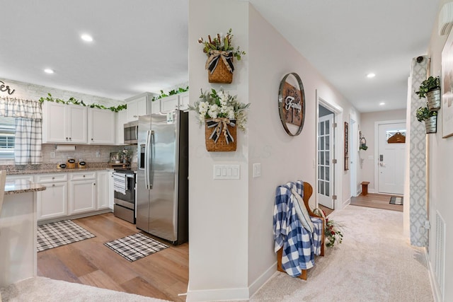 211 Talla Rd S, Delaware, OH 43015 - kitchen featuring appliances with stainless steel finishes, light wood finished floors, white cabinets, decorative backsplash, and light stone counters