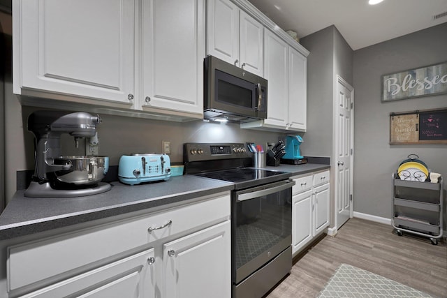 7911 Ashenden Dr, Blacklick, OH 43004 - kitchen with range with electric cooktop, light wood finished floors, white cabinetry, dark countertops, and recessed lighting