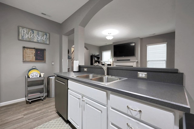 7911 Ashenden Dr, Blacklick, OH 43004 - kitchen with arched walkways, dark countertops, light wood-style floors, white cabinets, and open floor plan