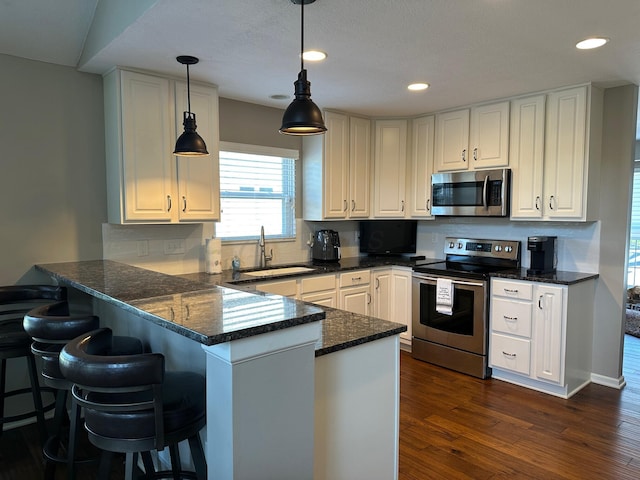 1013 Bluff Crest Dr, Columbus, OH 43235 - kitchen with stainless steel appliances, a peninsula, pendant lighting, white cabinetry, and recessed lighting