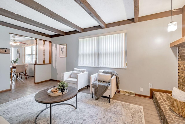 7472 Davis Rd, Hilliard, OH 43026 - living area featuring beam ceiling, wood finished floors, ceiling fan, and a brick fireplace