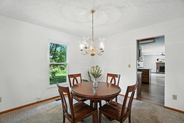 526 Springwood Lake Dr, Columbus, OH 43230 - dining space featuring a chandelier, dark colored carpet, a textured ceiling, and a brick fireplace