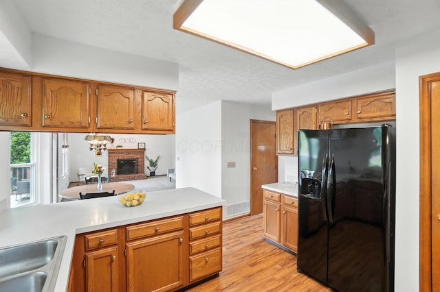 526 Springwood Lake Dr, Columbus, OH 43230 - kitchen featuring black fridge, a peninsula, a fireplace, light countertops, and brown cabinetry