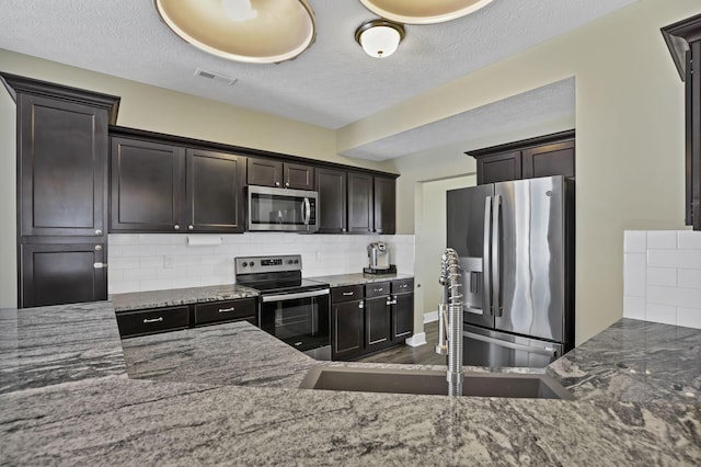 68 Asbury Ave, Newark, OH 43055 - kitchen featuring stainless steel appliances, stone counters, decorative backsplash, a textured ceiling, and dark brown cabinetry