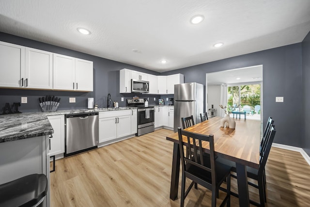 1815 Union St, Lancaster, OH 43130 - kitchen with appliances with stainless steel finishes, light wood-style flooring, white cabinets, recessed lighting, and dark stone countertops