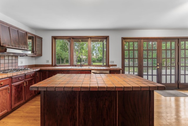 1054 Highland Dr, Columbus, OH 43220 - kitchen with stainless steel appliances, tile countertops, light wood finished floors, under cabinet range hood, and a center island