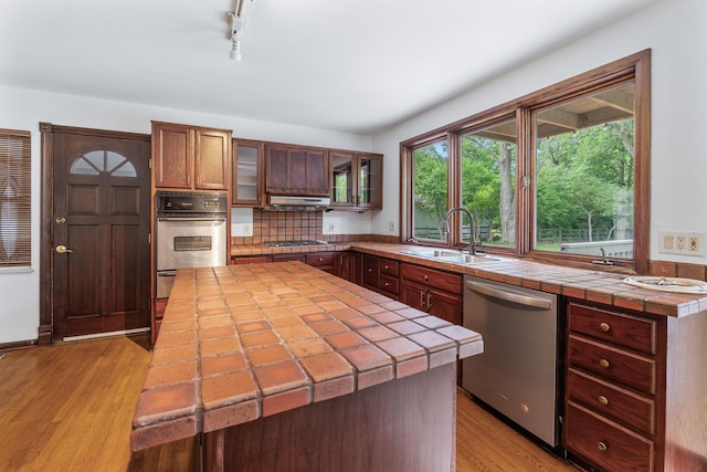 1054 Highland Dr, Columbus, OH 43220 - kitchen with stainless steel appliances, tile counters, light wood-style floors, tasteful backsplash, and track lighting
