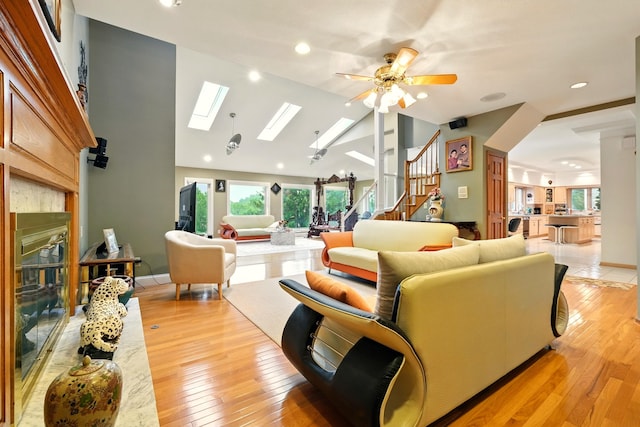 1515 Oak Run Ct, Mansfield, OH 44906 - living area with stairway, a skylight, a glass covered fireplace, light wood-style floors, and a ceiling fan