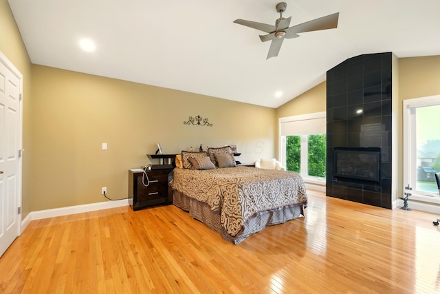 1515 Oak Run Ct, Mansfield, OH 44906 - bedroom featuring light wood-type flooring, multiple windows, lofted ceiling, a tiled fireplace, and ceiling fan