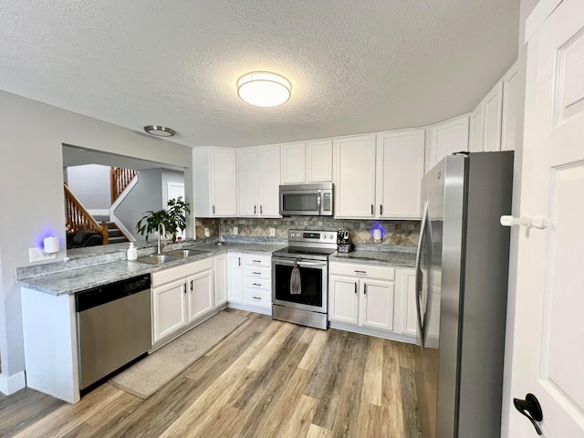 6871 Manor Crest Ln, Canal Winchester, OH 43110 - kitchen featuring appliances with stainless steel finishes, light wood-style flooring, white cabinets, decorative backsplash, and light stone countertops