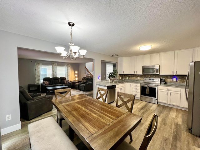 6871 Manor Crest Ln, Canal Winchester, OH 43110 - dining space with light wood-style floors, a chandelier, and a textured ceiling