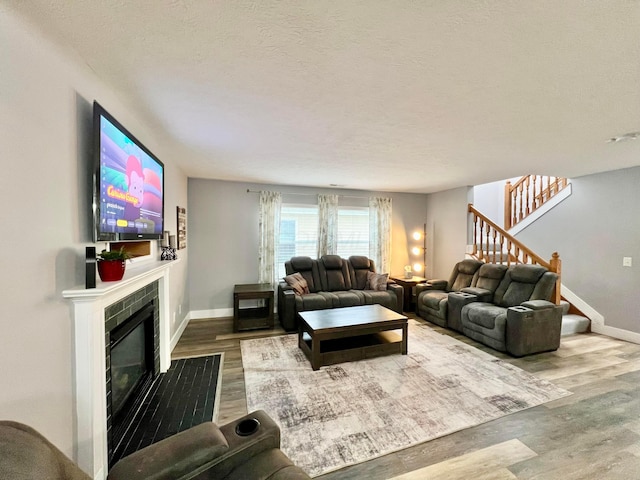 6871 Manor Crest Ln, Canal Winchester, OH 43110 - living area with wood finished floors, a tiled fireplace, stairs, and a textured ceiling