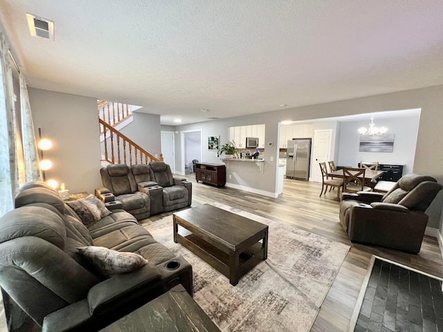 6871 Manor Crest Ln, Canal Winchester, OH 43110 - living area featuring a chandelier, stairway, light wood-style flooring, and a textured ceiling