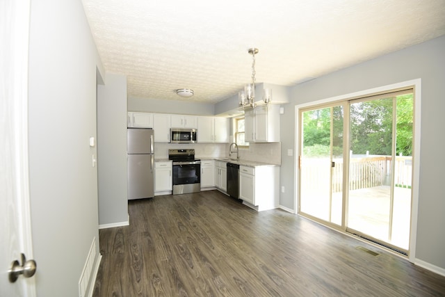 3565 Motts Place Ct, Canal Winchester, OH 43110 - kitchen featuring appliances with stainless steel finishes, white cabinetry, dark wood finished floors, decorative light fixtures, and a textured ceiling