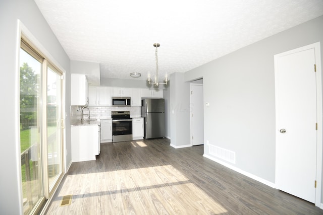 3434 Royal Hill Dr, Columbus, OH 43223 - kitchen featuring appliances with stainless steel finishes, light countertops, dark wood finished floors, a textured ceiling, and white cabinets
