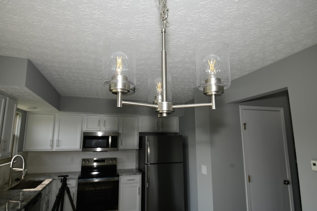 3434 Royal Hill Dr, Columbus, OH 43223 - kitchen featuring freestanding refrigerator, range with electric stovetop, stainless steel microwave, a textured ceiling, and white cabinets