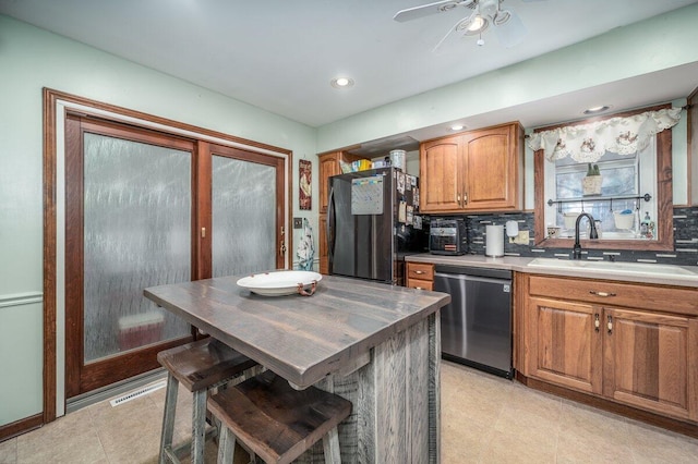 537 Dunkle Rd, Circleville, OH 43113 - kitchen featuring stainless steel dishwasher, freestanding refrigerator, brown cabinets, ceiling fan, and backsplash