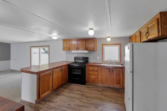264 Timberline Dr, Circleville, OH 43113 - kitchen with freestanding refrigerator, black gas range oven, a peninsula, under cabinet range hood, and brown cabinetry